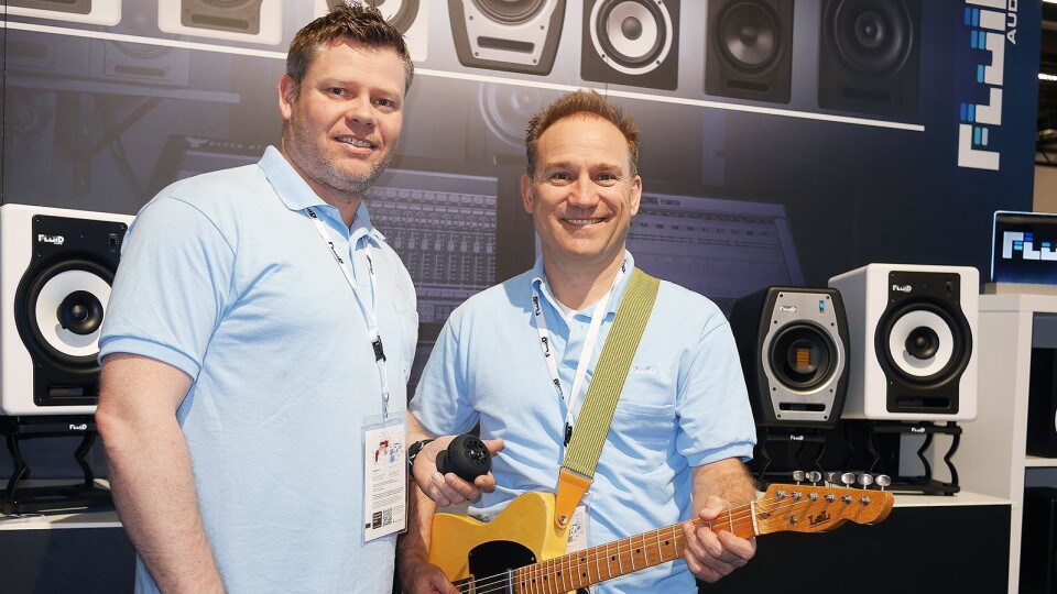 Kenneth Rustad (t. v.) og Kevin Zuccaro eier og driver Fluid Audio sammen. Her viser de gitarhøyttaleren Strum Buddy, i bakgrunnen noen av studiomonitorene og høyttalerstativene de leverer. Foto: Stian Sønsteng