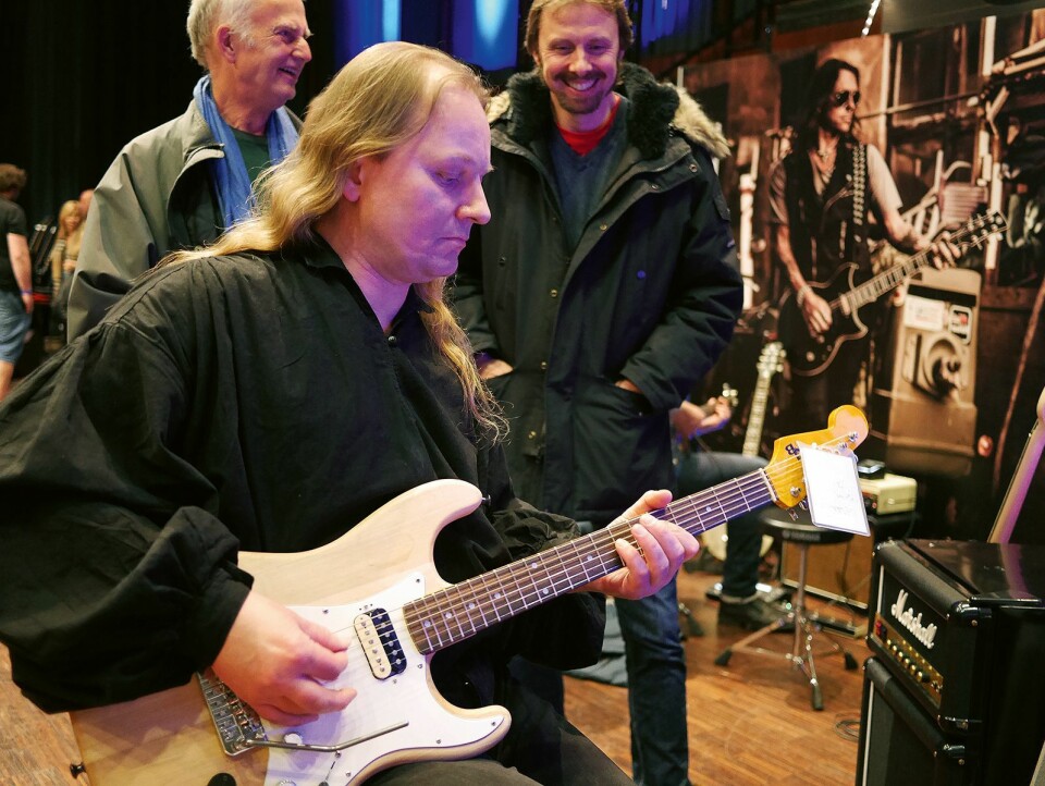 Jan Sverre Braathen (t. v.) og Eivind Staxrud i hjertelig samtale, mens Lars Levin prøvespiller en JB-gitar. Foto: Stian Sønsteng