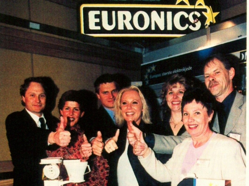 Administrasjonen i Euronics Norge i 2001 med den nye logoen. F. v. Kenneth Baltzersen, Solgunn Øvereng, Asle Bjerkebakke, Anne Line Svendsen, Kari Ann Jensen, Gunni Hansen og Terje Gudmundsen. Foto: Erik Andersen.