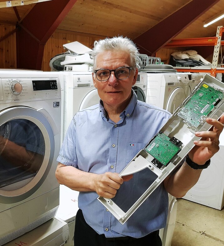 Tommy Paulsen med et styringskort til en vaskemaskin, en modul de ofte bytter. Foto: Jan Røsholm