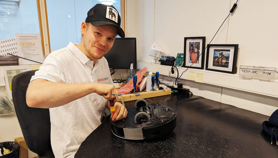 Mathias Grønnvoll skrur på en robotstøvsuger fra Ecovacs. Foto: Stian Sønsteng